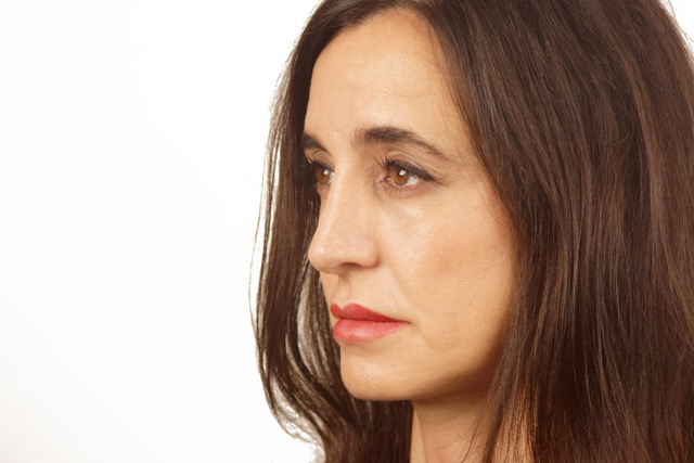 A headshot of Laura staring away from the camera. She is wearing red lipstick. The background is white.